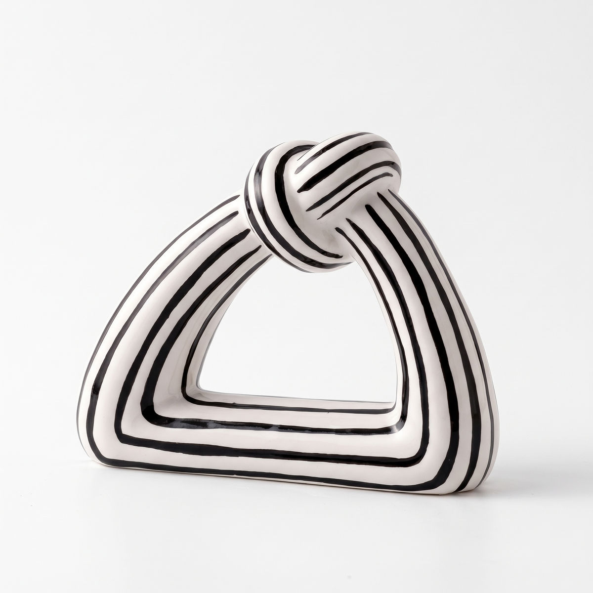 Black and white striped ceramic knot sculpture on a white background