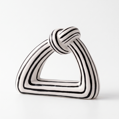 Black and white striped ceramic knot sculpture on a white background