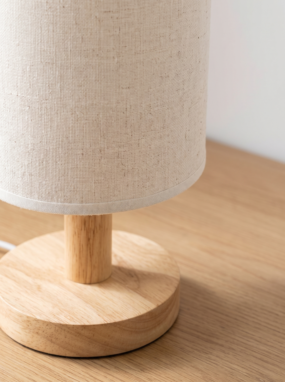 Close view of a linen shade and wooden lamp base