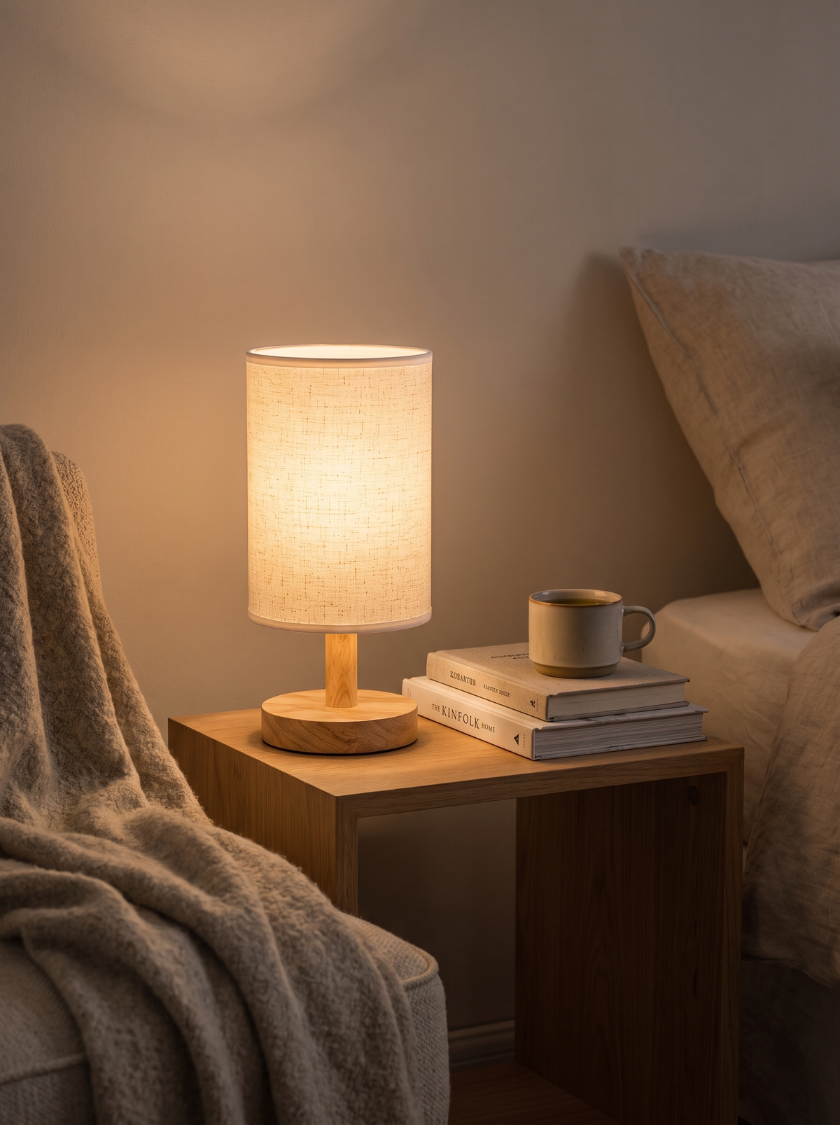 Linen shade lamp lit on a bedroom nightstand