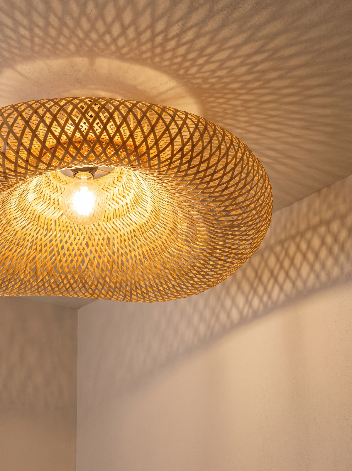 Bamboo pendant casting patterned shadows on a ceiling