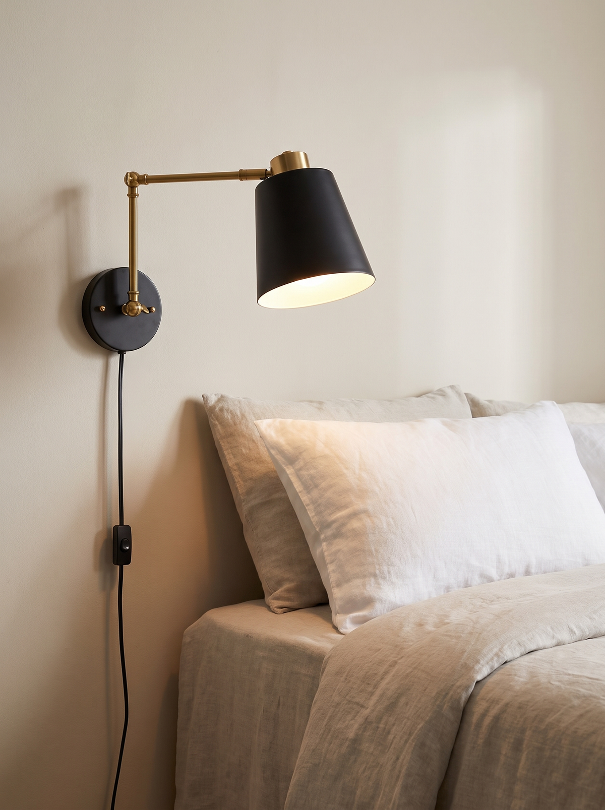 Swing arm wall sconce angled over a bed